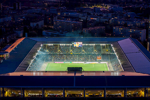 Nahe Luftaufnahme des Innenraums des Wankdorfstadions, mit sichtbarem Spielfeld, Zuschauertribünen und der umgebenden Wohnbebauung.